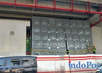 Petugas memasang garis polisi pada tandon air proyek pembangunan LRT yang jebol di Jalan Rasuna Said, Jakarta Selatan, Rabu (29/6/2022).