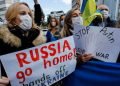 Warga Ukraina yang tinggal memegang poster dan bendera selama demonstrasi mengecam Rusia atas tindakannya di Ukraina, dekat kedutaan Rusia. FOTO/REUTERS/Issei Kato/WSJ/sad.