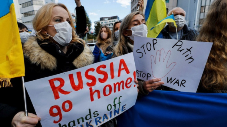 Warga Ukraina yang tinggal memegang poster dan bendera selama demonstrasi mengecam Rusia atas tindakannya di Ukraina, dekat kedutaan Rusia. FOTO/REUTERS/Issei Kato/WSJ/sad.