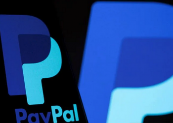 Logo PayPal terlihat pada smartphone di depan logo yang sama yang diambil pada Rabu (8/9/2021).